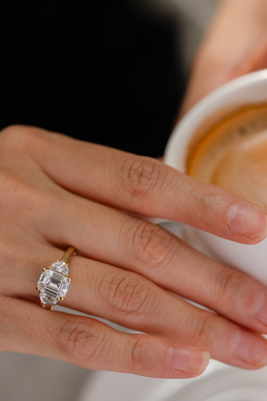Emerald-cut diamond three-stone mezzaluna engagement ring with half-moon design, showcasing sparkling diamonds and elegant craftsmanship.